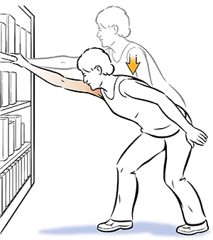 Femme faisant des exercices d'élévation des épaules, en se tenant à une bibliothèque.